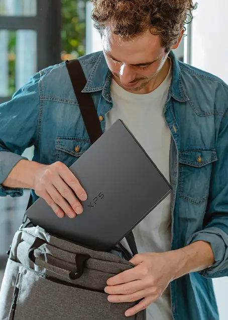Mężczyzna wkładający smukłego laptopa Dell XPS 14 do torby