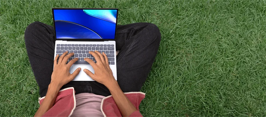 Osoba pracująca na laptopie XPS 13 na trawie