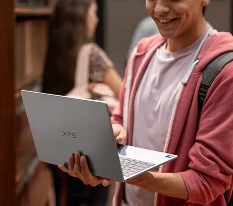 Uśmiechnięty mężczyzna trzymający otwarty laptop XPS 13 na jednej dłoni